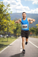 Male athlete running on a track and pointing at his race number