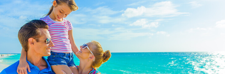 Family at the beach, mother, father and daughter, close-up, dressed in colorful tropical outfits