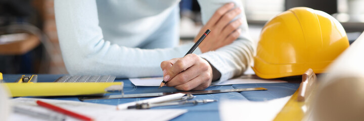 Designer builder hands draw drawing on table.