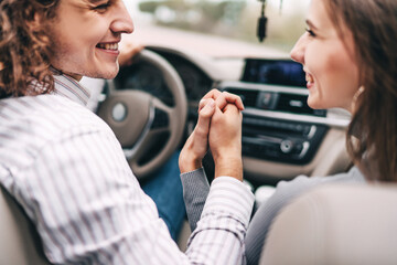 Fototapeta na wymiar Close up front of a luxury car holding hands with a guy and a girl and smiling at each other
