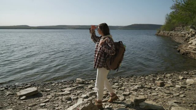 Beautiful woman in sensible clothes with backpack on shoulder hiking alone at national park Podillya Tovtry. Concept of people, hobby and leisure time.
