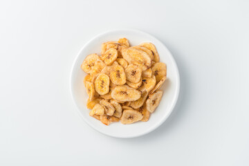 A plate of banana chips on a light background. Top view.