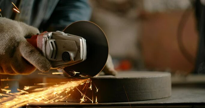 Locksmith cuts sheet metal with a grinder with a lot of sparks in slow motion, metalwork at workshop, 4k 60p Prores HQ