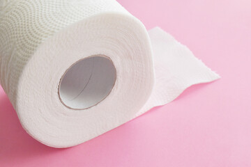 Toilet paper roll on pink background. Copy space is on the right side.  Flat lay top view photo.