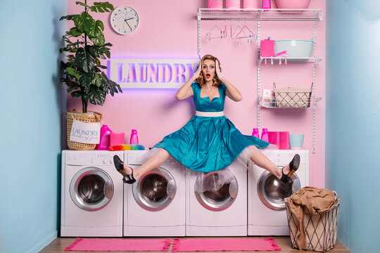 housewife in laundry is shocked. The concept of female unpaid domestic work. Beautiful woman with makeup and styling washes dirty clothes. Doll in the dollhouse model photo session.  housekeeper tired