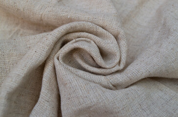 Natural linen fabric, twisted in the center into a spiral. Textile background