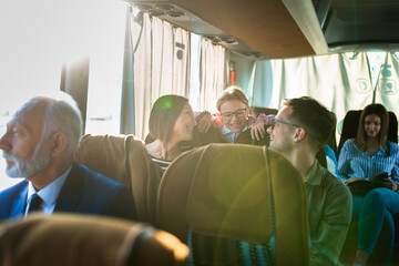 Family traveling by bus, smiling and talking together.