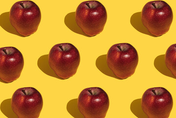 Pattern of red apples on a yellow background. Creative food concept.