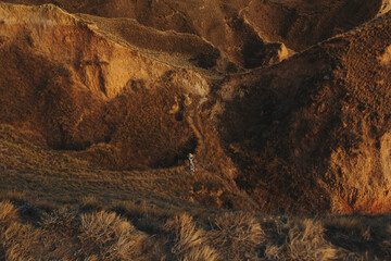 top view of a textured orange landscape and a girl in a hat making a photo with a smartphone