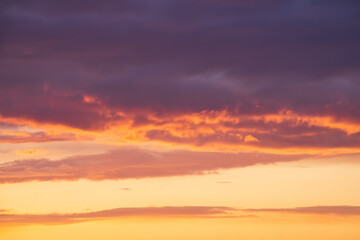 Bright violet or purple clouds at epic orange sunset sky background.