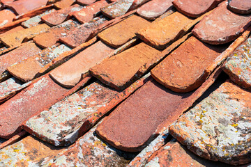 Inverted, upside down terracotta roof tiles covered with lichen and moss