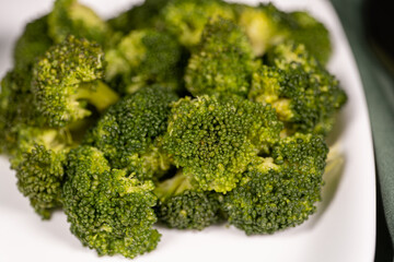 healthy food, boiled broccoli on a white plate on a dark green cloth