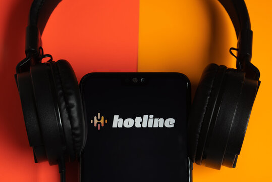 Hotline app logo seen on the smartphone with headphones. Hotline platform is a new drop in audio chat developed by Facebook, competitor to popular Clubhouse app. Stafford, UK, April 8, 2021