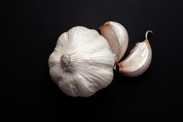 still life of garlic heads and garlic cloves on black background.  healthy ingredients food concept.