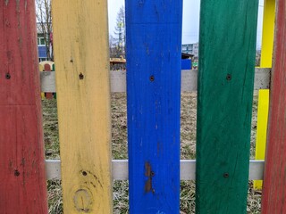 worn out and multicolored wooden fence in spring at daytime