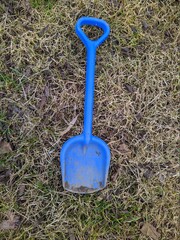 children's blue plastic shovel on the ground