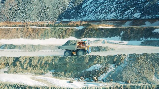 Truck loaded with ore is driving through the mine site. Industrial quarry, heavy industrial machinery working at the mining open pit.