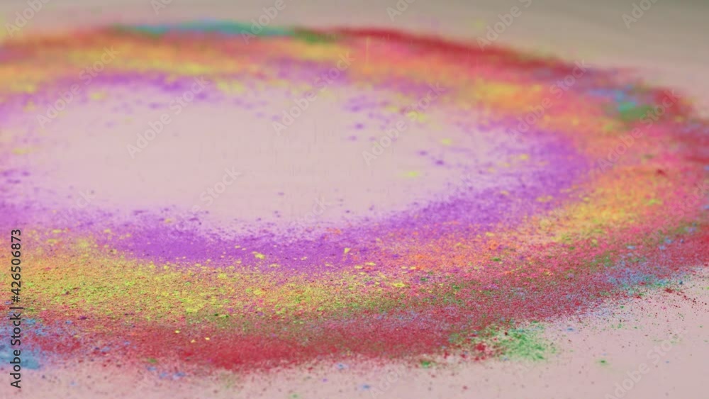 Poster sprinkle several colors of dust on the white paper that is spinning around until the dust is circula