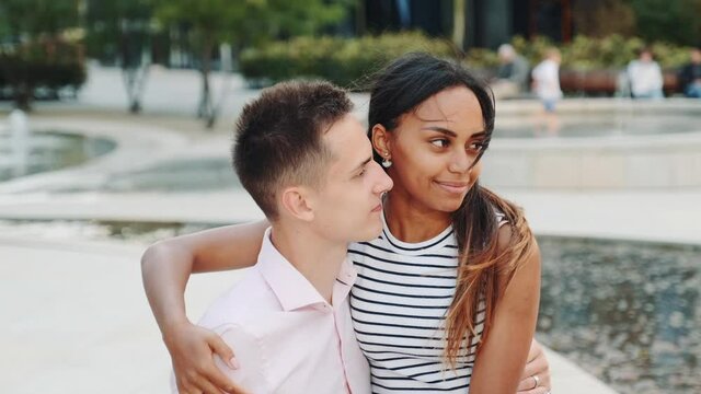 Handsome man and attractive black woman having date in a modern city park