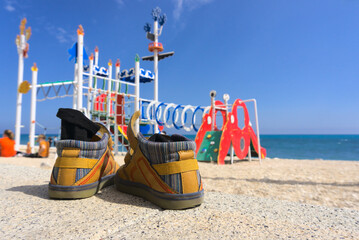 Child's shoes and socks laying on the ground next to a playground at the beach in Altea, Spain