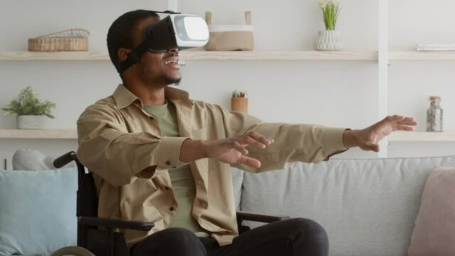Handicapped Black Guy Exploring Augmented Reality Sitting In Wheelchair Indoor