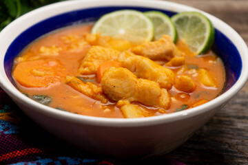 Fish soup with vegetables on wooden background. Mexican food