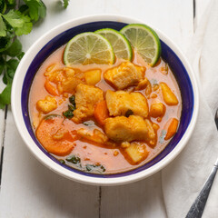 Fish soup with green lime and vegetables on white background. Mexican food