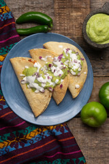 Fried tacos with guacamole and sour cream on wooden background. Mexican food