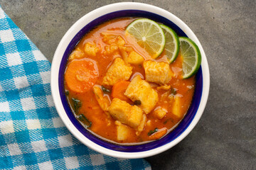 Fish soup with vegetables on grey background. Mexican food