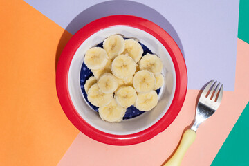 Cutted banana in bowl on colorful background