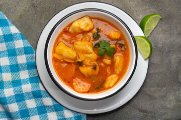 Fish soup with vegetables on grey background. Mexican food
