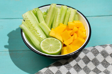 Cucumber and mango salad on turquoise background