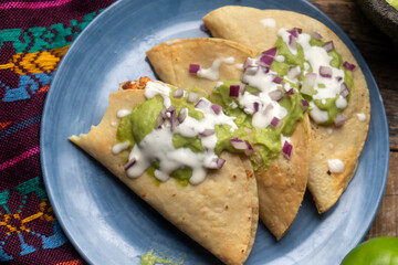 Fried tacos with guacamole and sour cream on wooden background. Mexican food