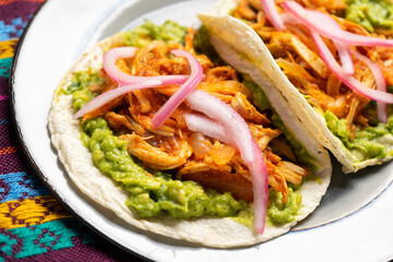 Chicken tinga tacos with guacamole and onion on rustic background. Mexican food
