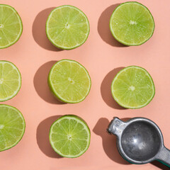 Cutted lime and squeezer on pink background