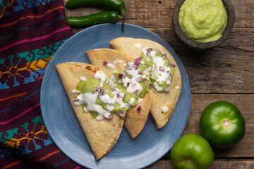Fried tacos with guacamole and sour cream on wooden background. Mexican food