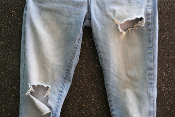 Torn blue Jeans on black gravel background. Denim texture with detail