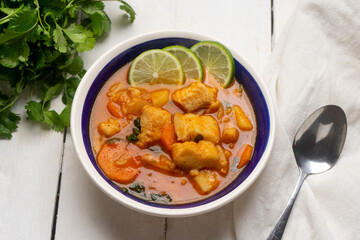 Fish soup with green lime and vegetables on white background. Mexican food