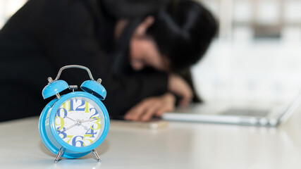 The blue alarm clock on the desk of a business man is sleeping