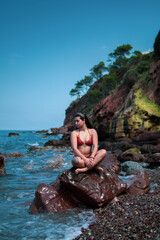 Mujer joven encima de las rocas del mar con las olas