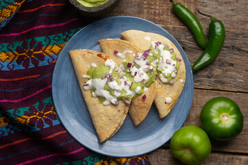 Fried tacos with guacamole and sour cream on wooden background. Mexican food