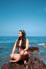 Fototapeta na wymiar Mujer joven encima de las rocas del mar con las olas
