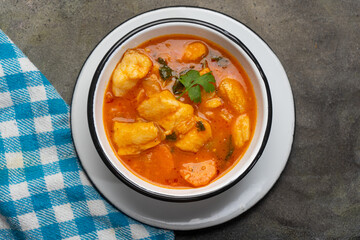 Fish soup with vegetables on grey background. Mexican food