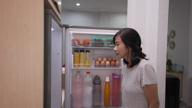 dissapointed woman while opening the fridge door before cooking