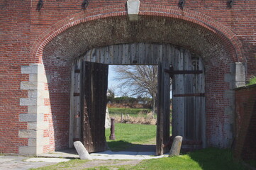 Colonial Arched Brick Doorway with Heavy Wooden Doors in Daylight