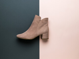 Light women's beige suede boot on a light beige background. Flat lay.
