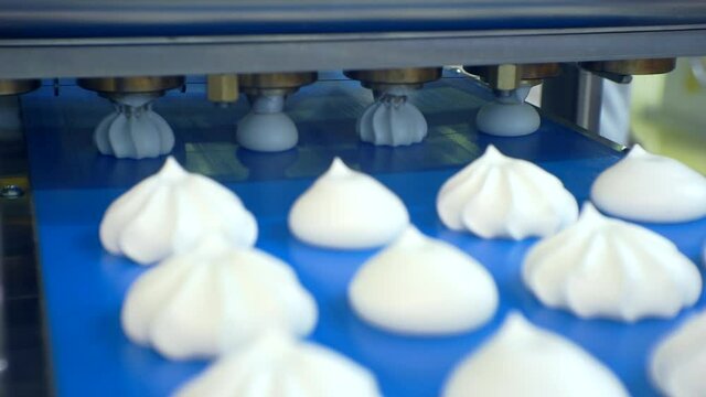 modern food production.moving background. a special machine makes pastry cakes from thick cream.finished cakes move along a conveyor belt. close-up. shallow depth of field.