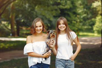 Fototapeta premium Two cute girls in a park playing with little dog