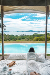 Happy woman traveler enjoy Beautiful ocean view, Tourist relaxing in tropical luxury resort with swimming pool. Leisure, travel and summer vacation concept