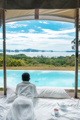 Happy man traveler enjoy Beautiful ocean view, Tourist relaxing in tropical luxury resort with swimming pool. Leisure, travel and summer vacation concept